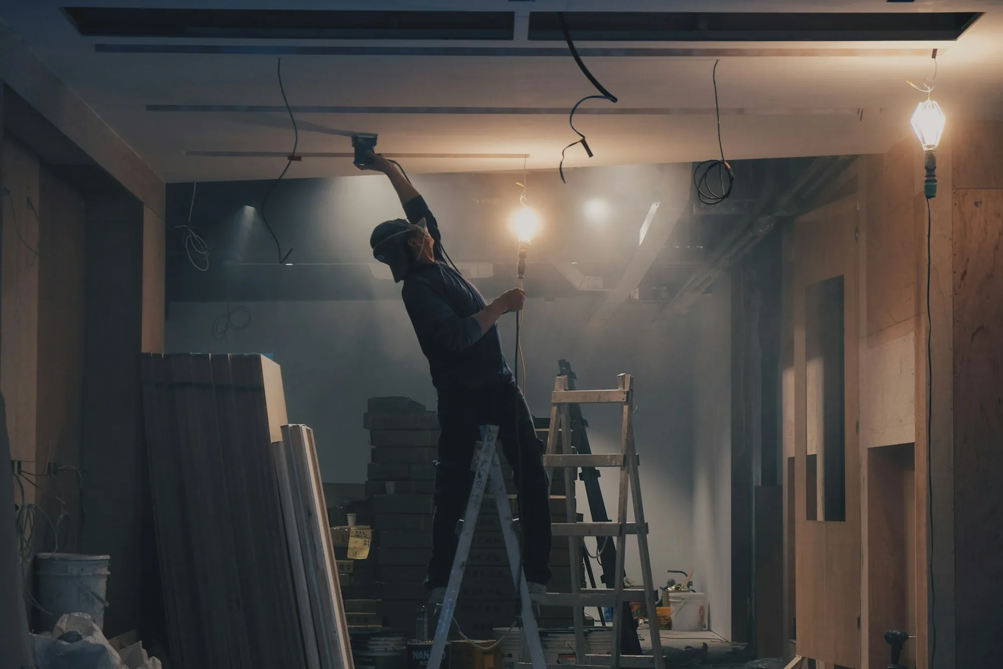 Worker on a ladder finishing a ceiling during a renovation
